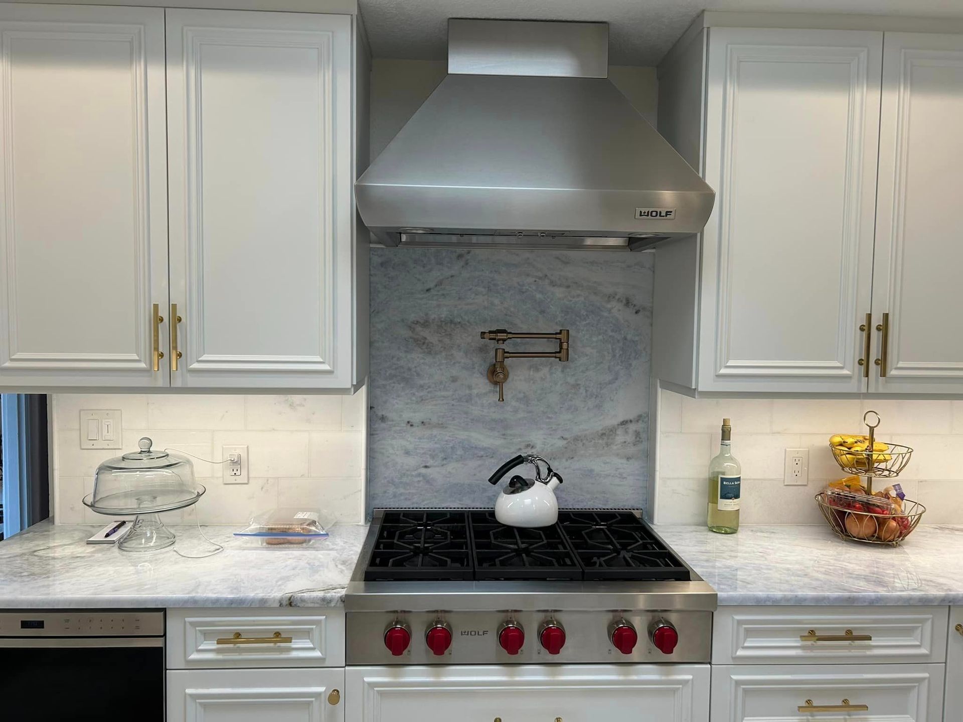 A kitchen with white cabinets and a stove top oven