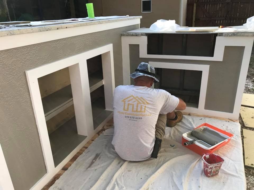 A man is kneeling down on a table painting a wall.