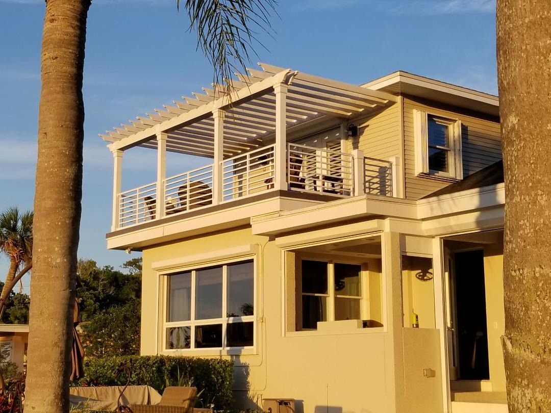 A house with a balcony and a palm tree in front of it