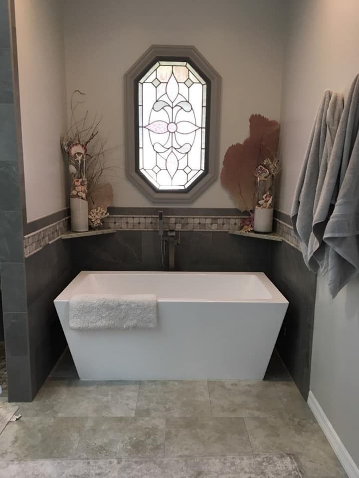 A bathroom with a bathtub and a stained glass window.
