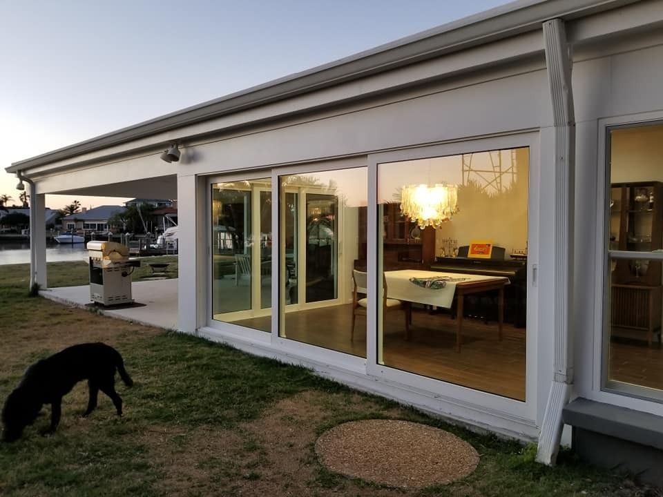 A dog is standing in front of a house with a lot of windows.