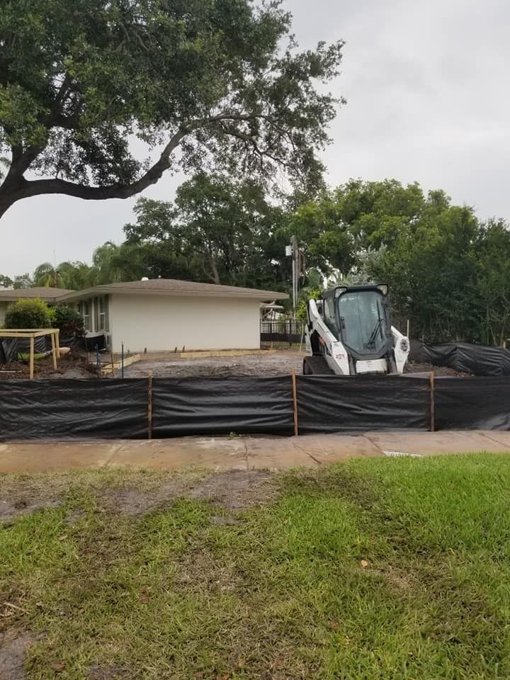 A bobcat is parked in front of a house behind a fence.