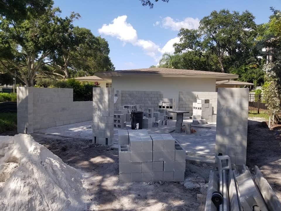 A pile of bricks sits in front of a house under construction