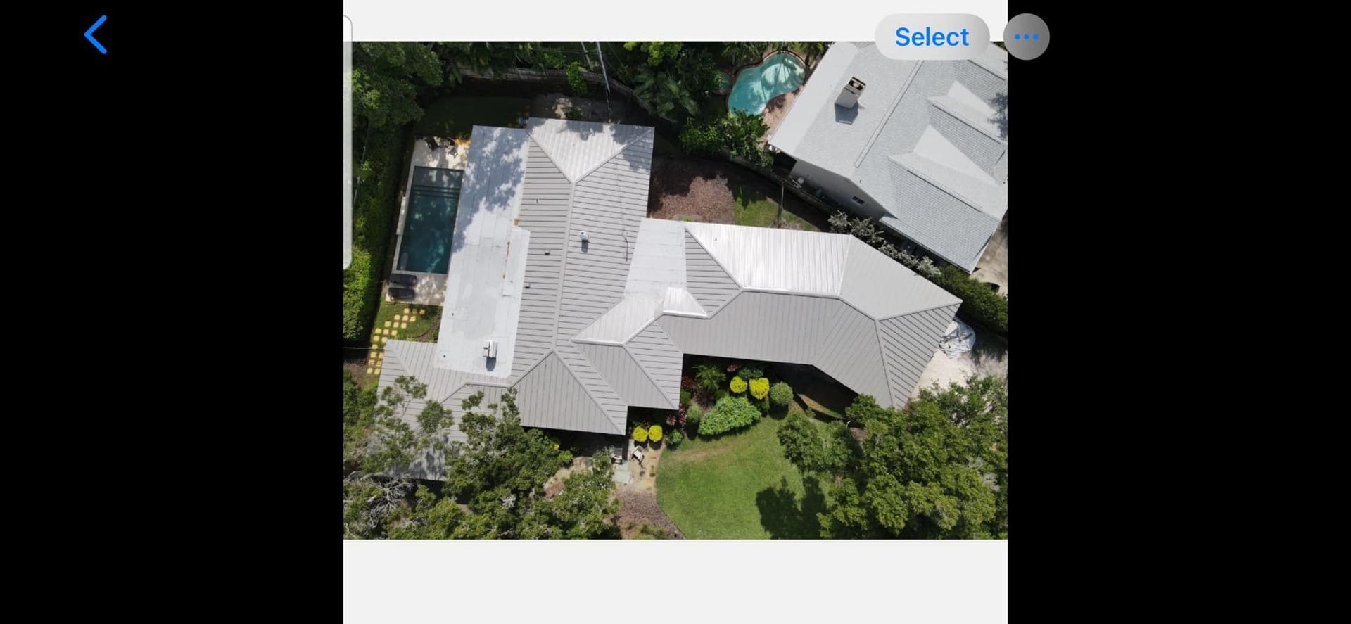An aerial view of a house with a pool and trees surrounding it.