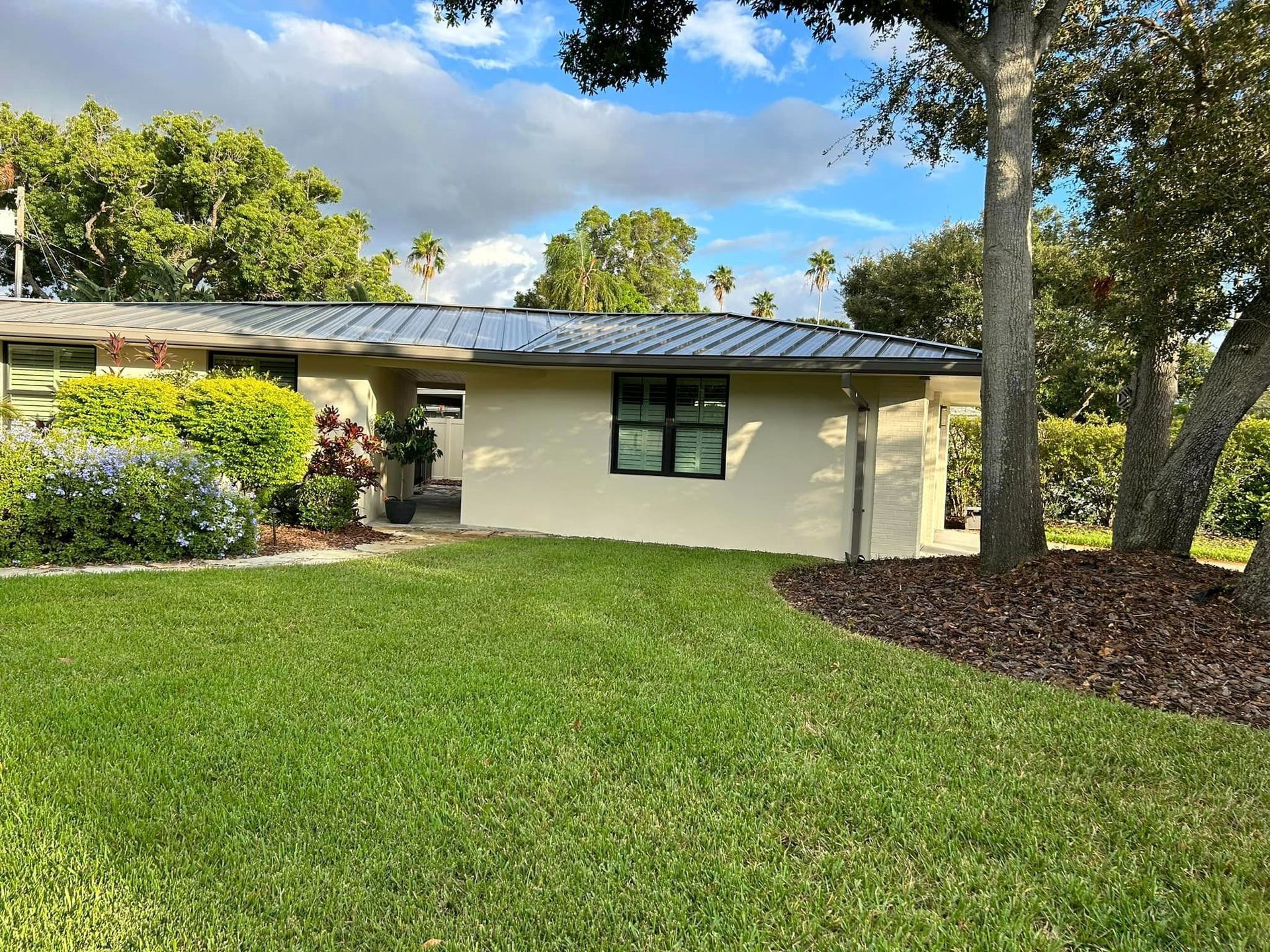 A house with a lush green lawn and trees in front of it.