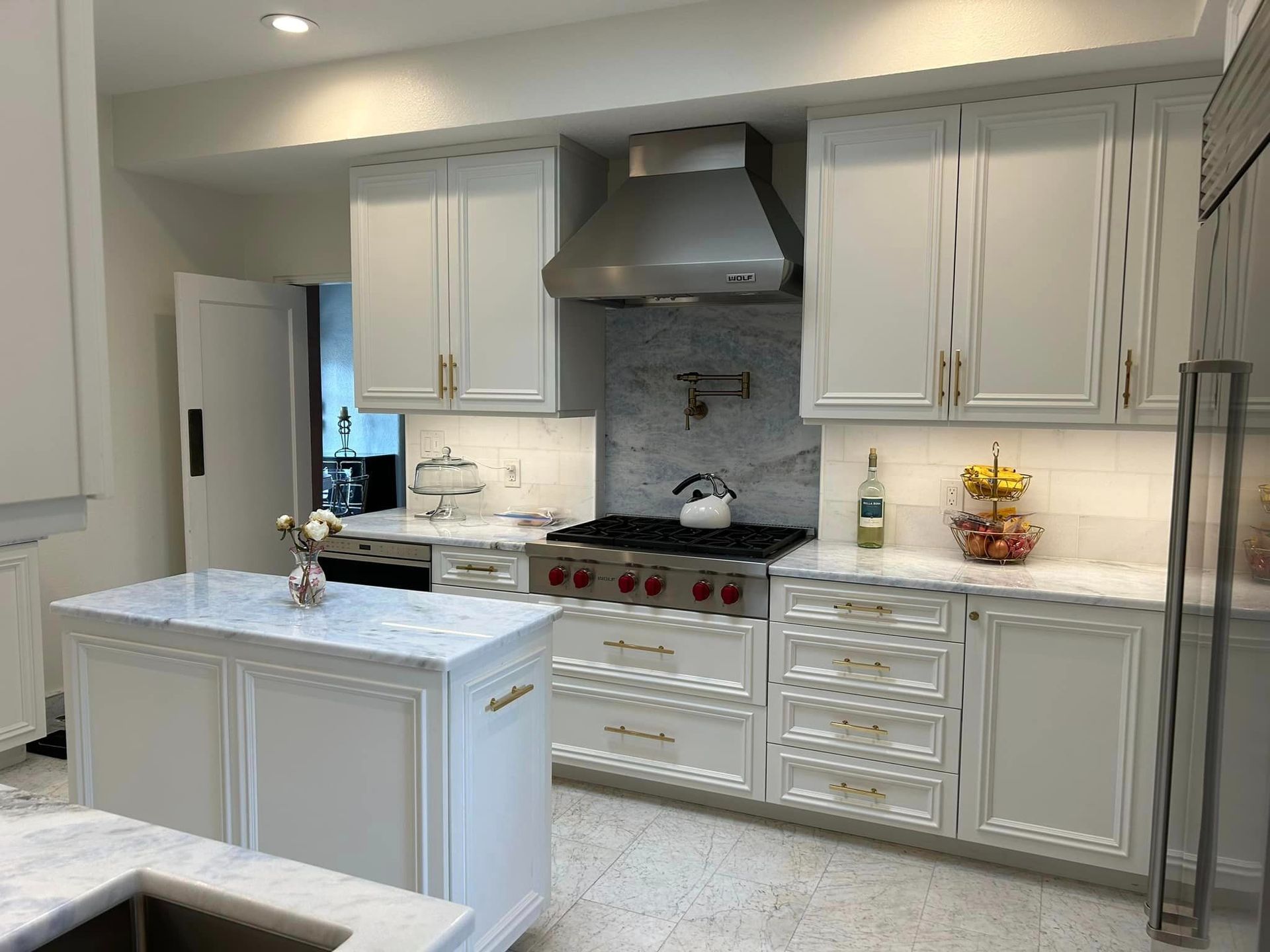 A kitchen with white cabinets , stainless steel appliances , a stove and a sink.