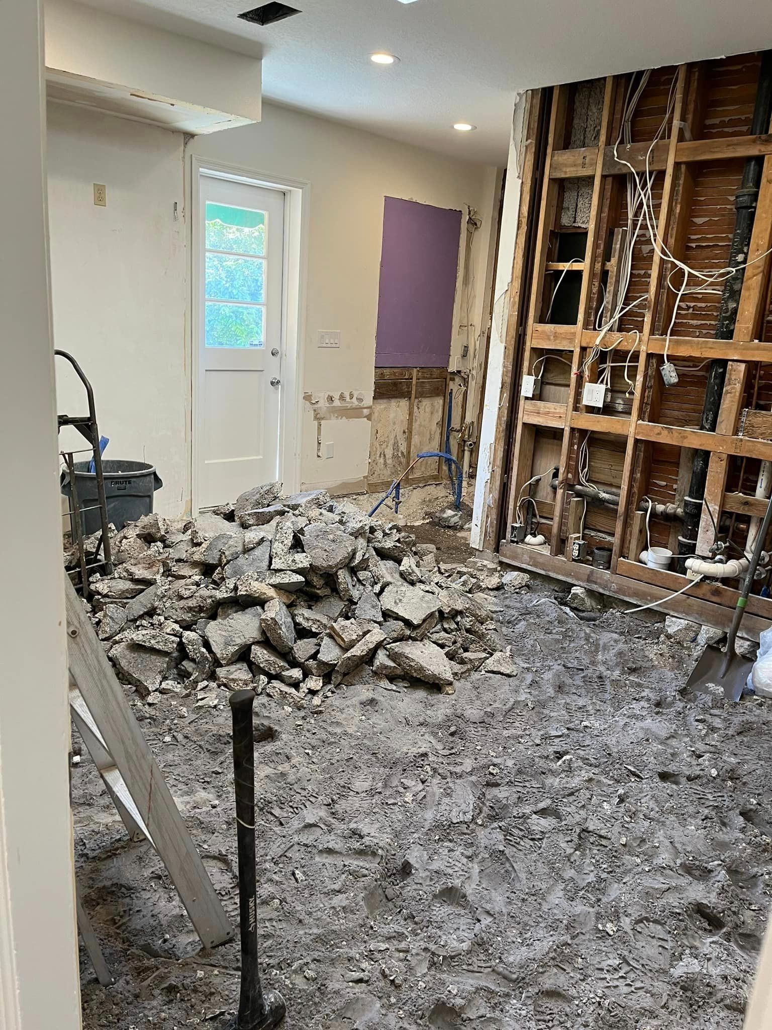A room with a lot of rocks on the floor and a hammer.