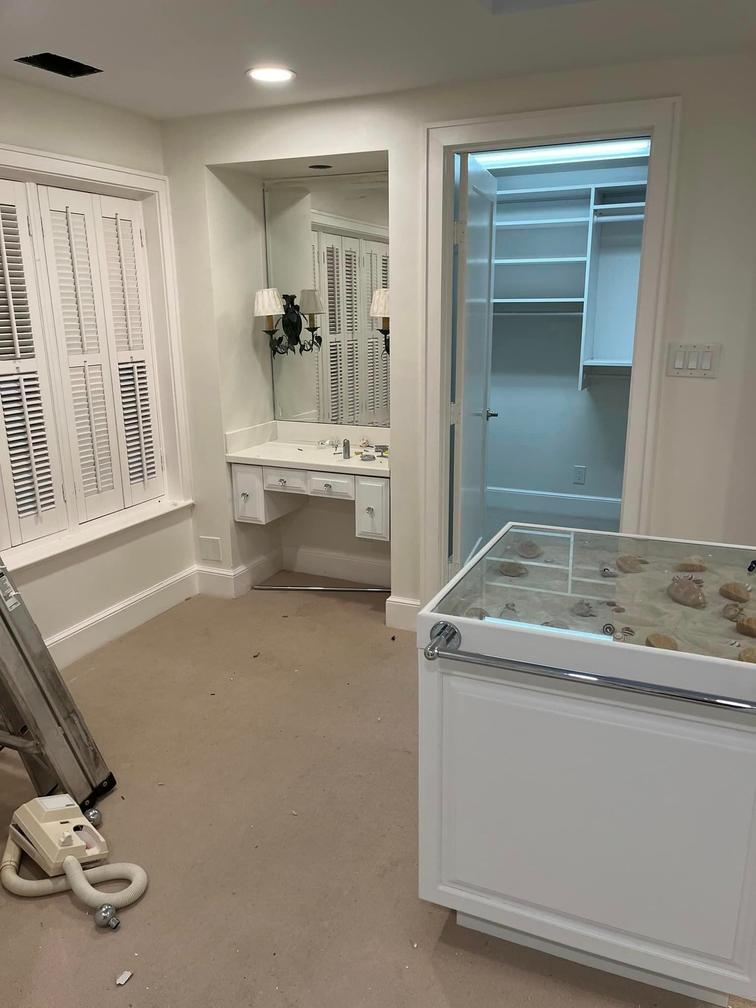A bathroom with a sink , mirror , and closet.
