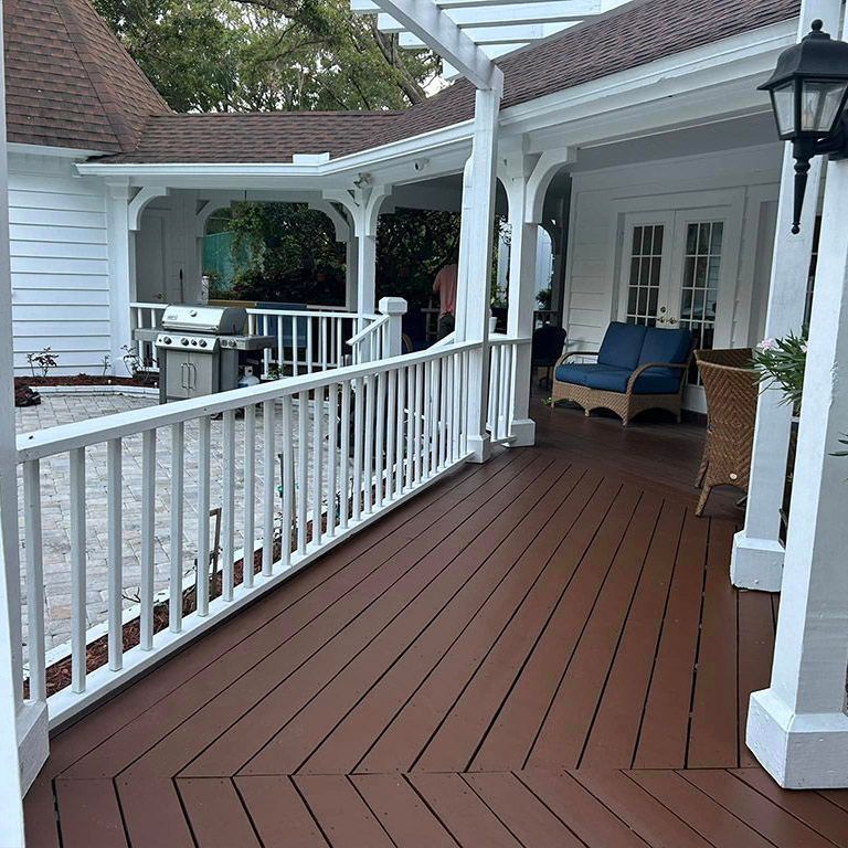 A porch with a white railing and a grill