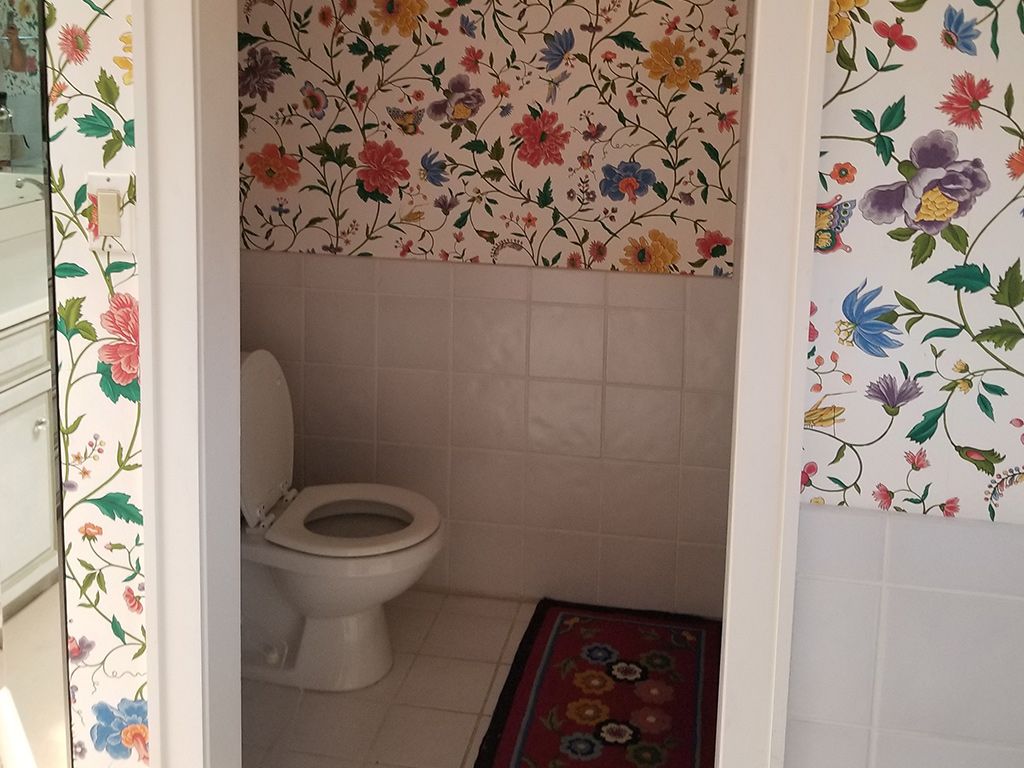 A bathroom with a toilet and floral wallpaper on the wall