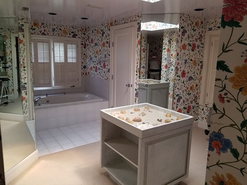 A bathroom with floral wallpaper and a table with seashells on it