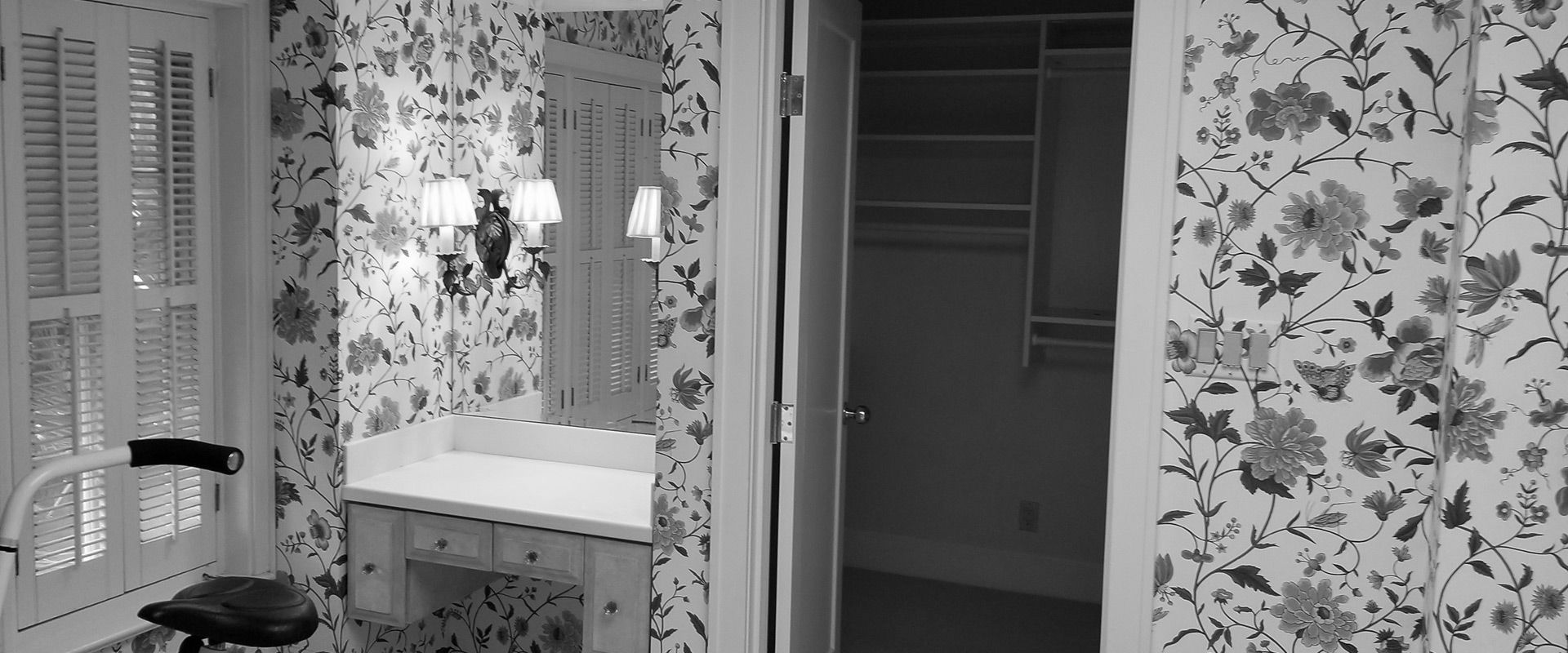 A black and white photo of a bathroom with floral wallpaper.