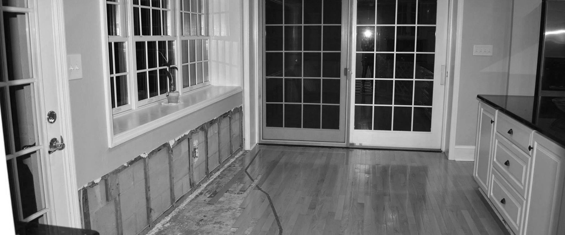 A black and white photo of a kitchen with sliding glass doors.
