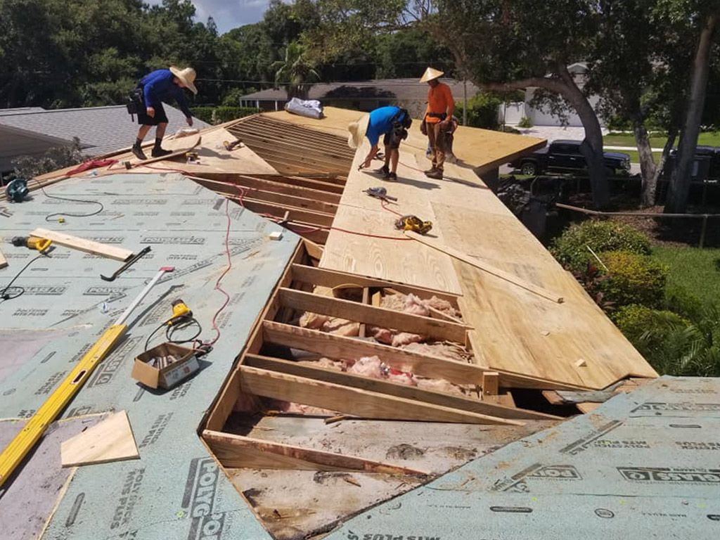 A group of men are working on a roof of a house.