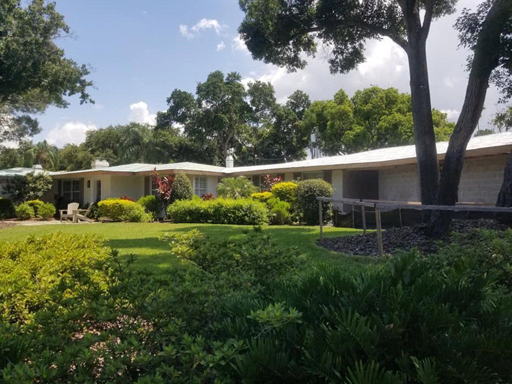 A house with a large lawn and trees in front of it