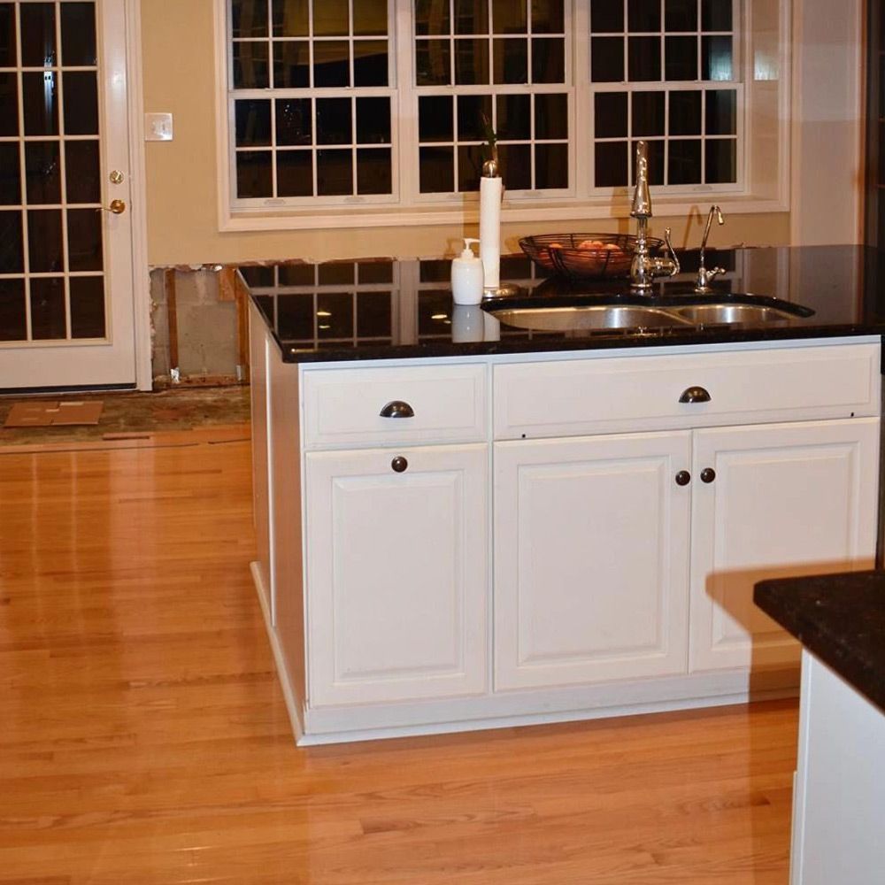 A kitchen with white cabinets and black counter tops