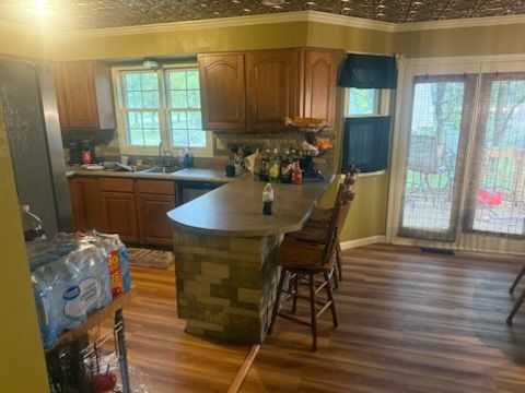 A split image comparing a finished bathroom with gray wood floors and vanity next to a bathroom during construction.
