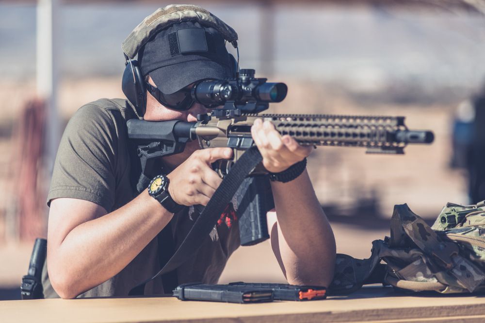 Person Aiming a Rifle With a Scope, Wearing a Cap, Headphones, and Sunglasses — Mackay Shooters Supplies in Paget, QLD