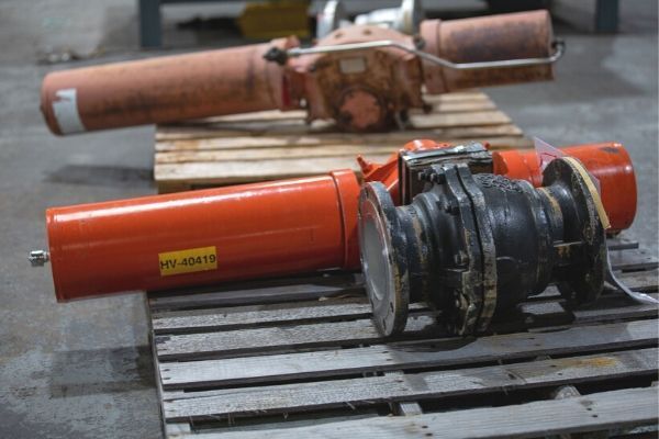 Two orange-and-black industrial tools lying on wooden pallets in a warehouse.