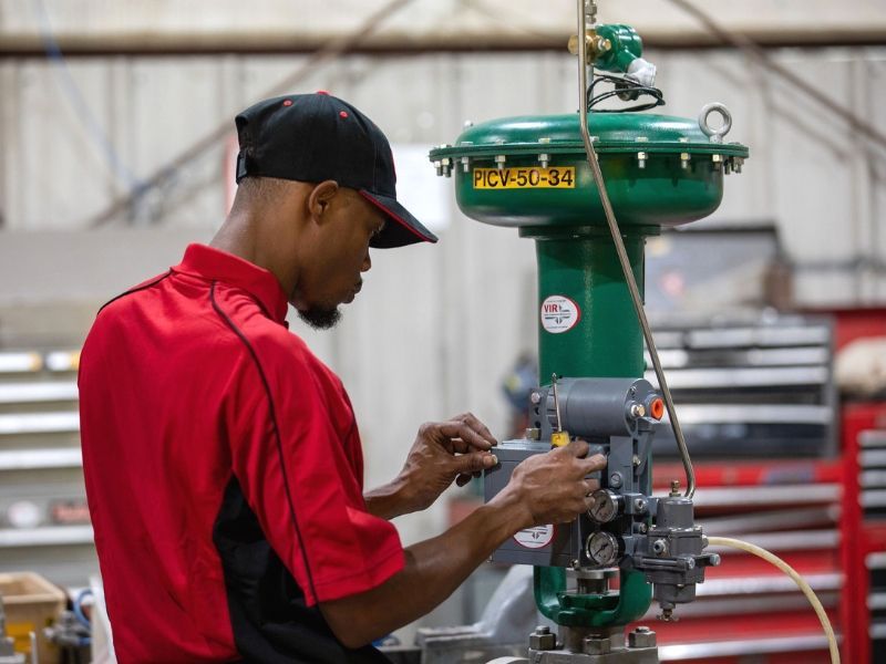 Worker in red shirt adjusting machinery in a workshop