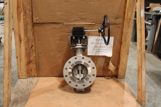 Industrial valve with handwheel mounted on a wooden crate in a workshop setting