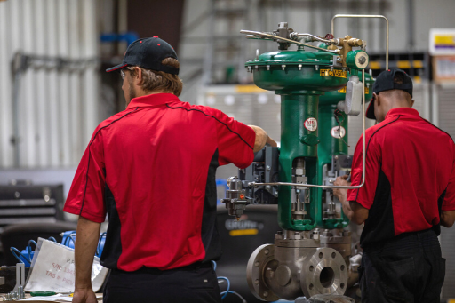 Two workers in red shirts inspecting industrial machinery in a factory workshop