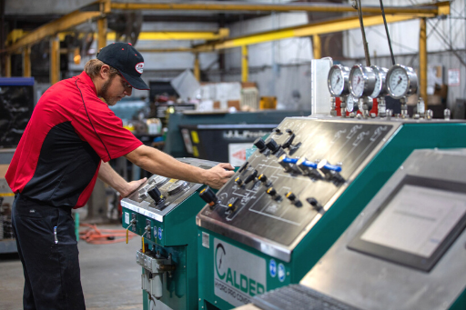 Worker in red shirt operating industrial machinery in a factory workshop.