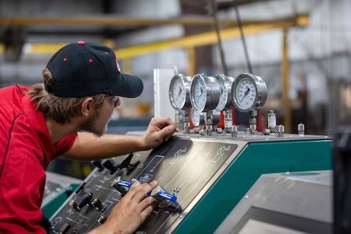 Mechanic in red shirt working on a green machine in a workshop