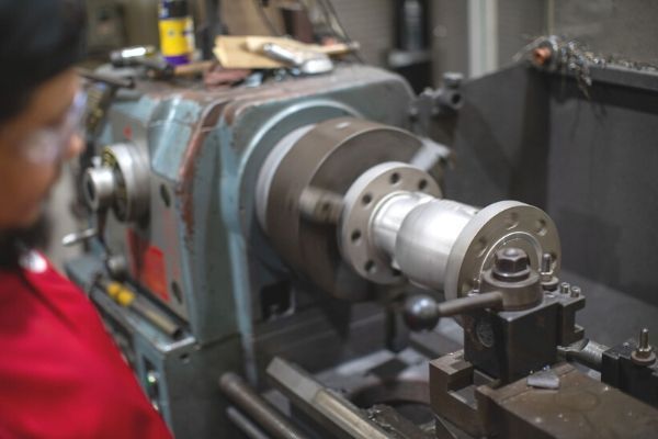 Worker operating a metal lathe in an industrial workshop