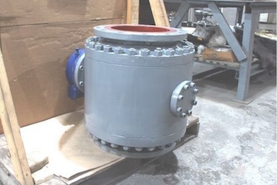 Large gray industrial pressure vessel with bolted flanges in a workshop, viewed from the side.