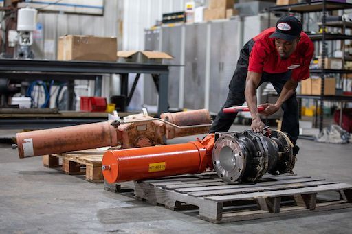 Worker in red shirt moving industrial machinery on pallets in a warehouse workshop