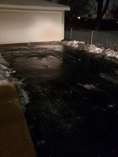 There is a lot of snow on the ground in the driveway.