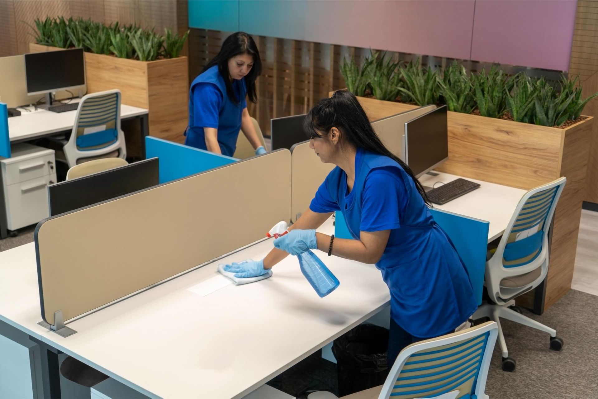 Two women are cleaning a desk in an office.