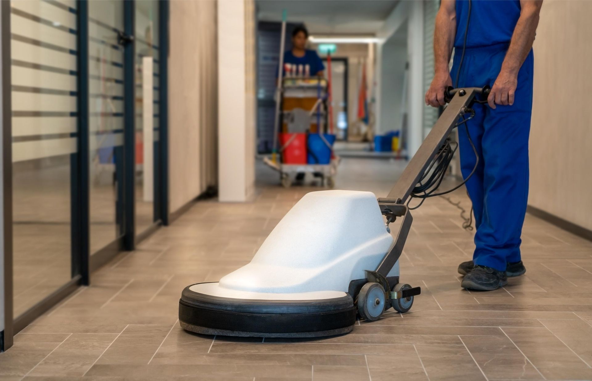 A man is cleaning the floor with a machine in a hallway.