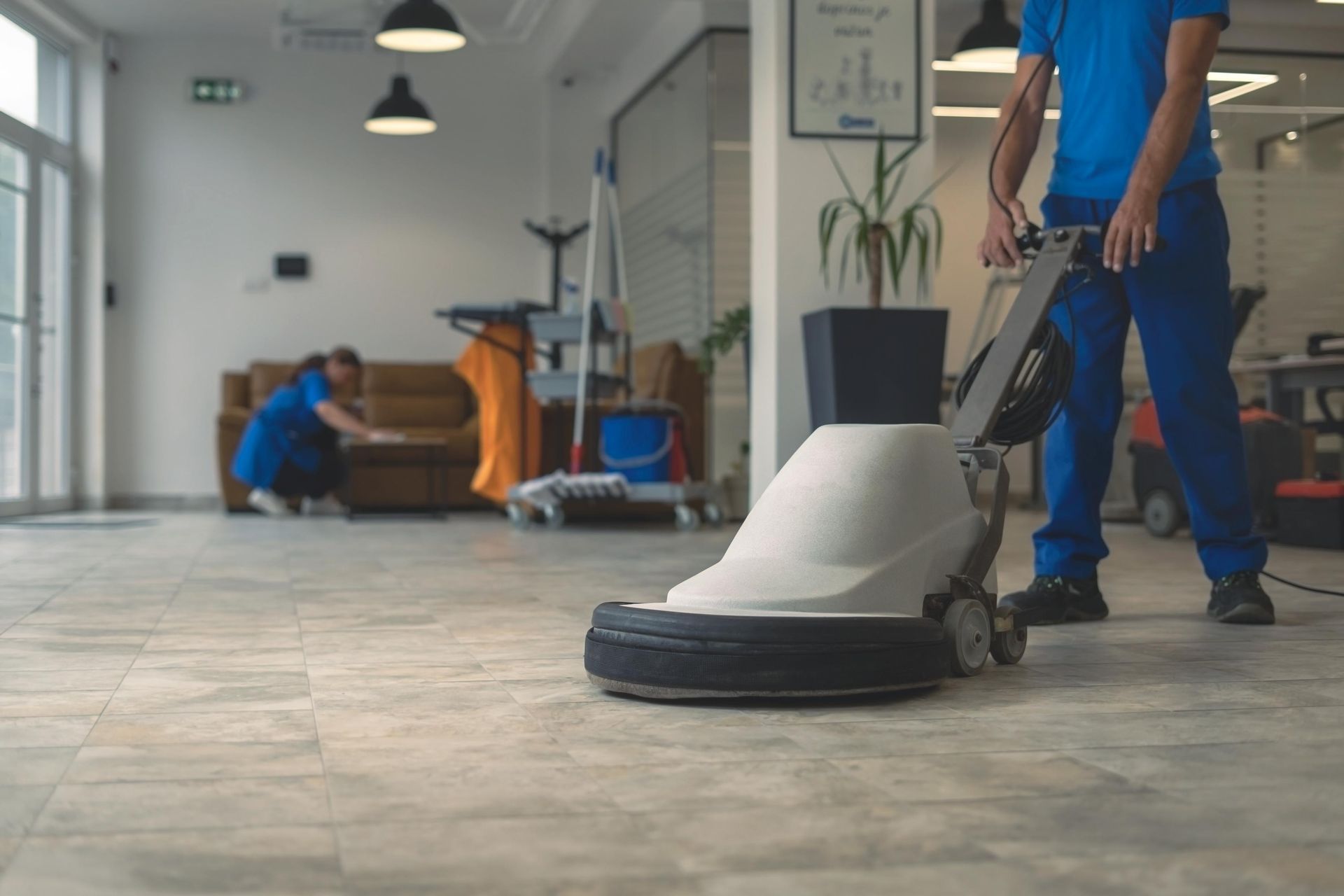 A man is cleaning the floor with a machine in an office.