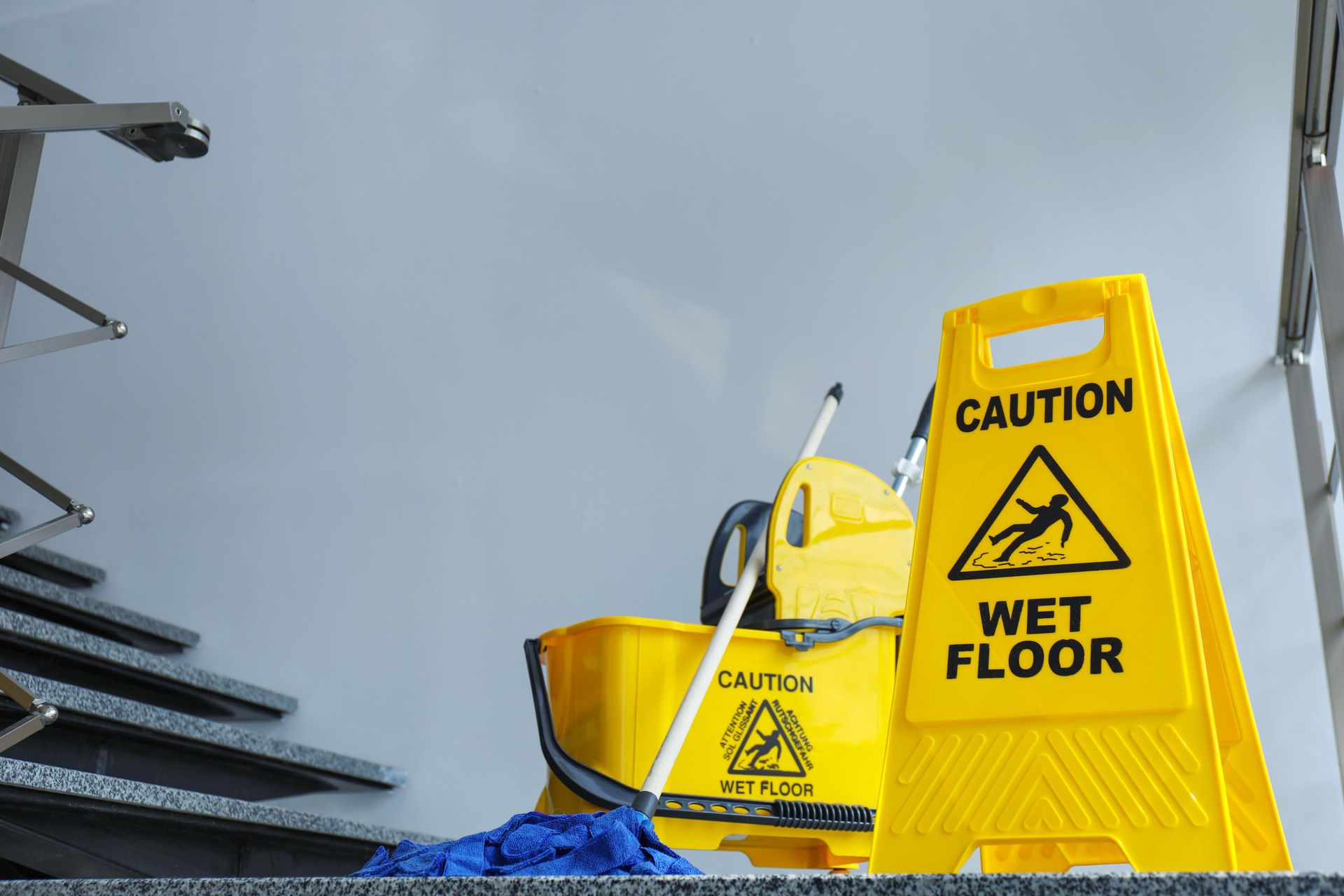 A yellow caution wet floor sign is next to a mop and bucket.