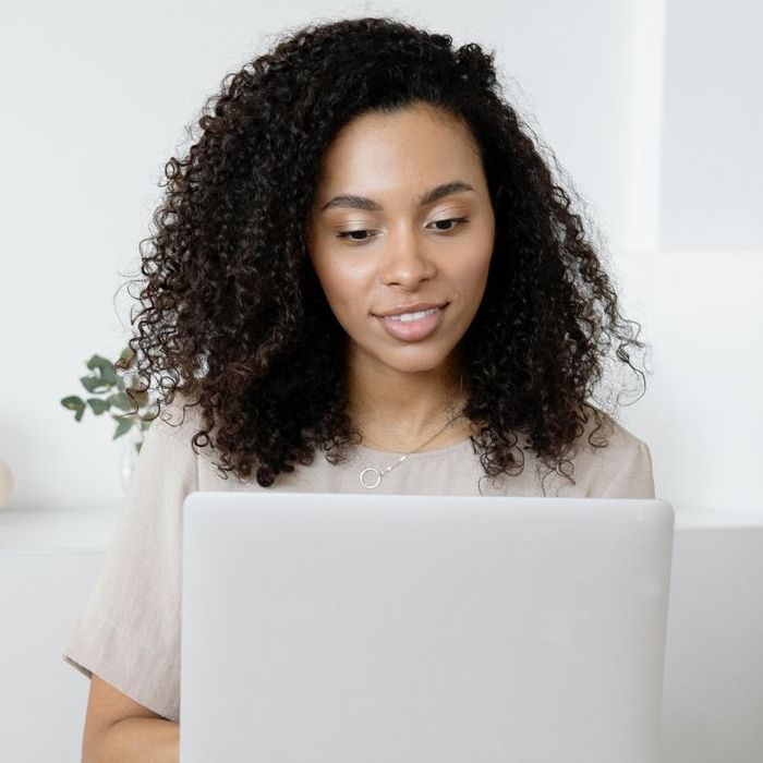 A woman with curly hair is using a laptop computer.