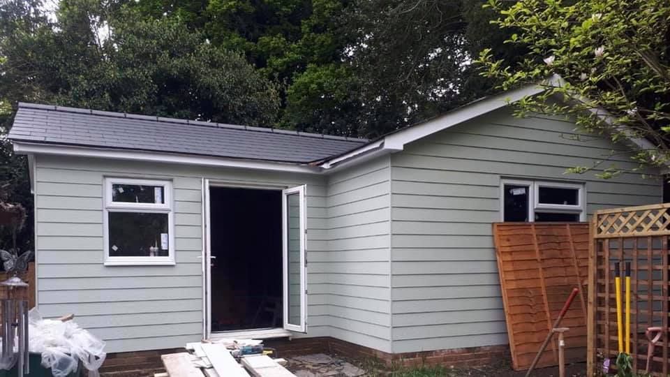 A small house with a black roof is being built in the backyard, by Pro Build East Ltd.