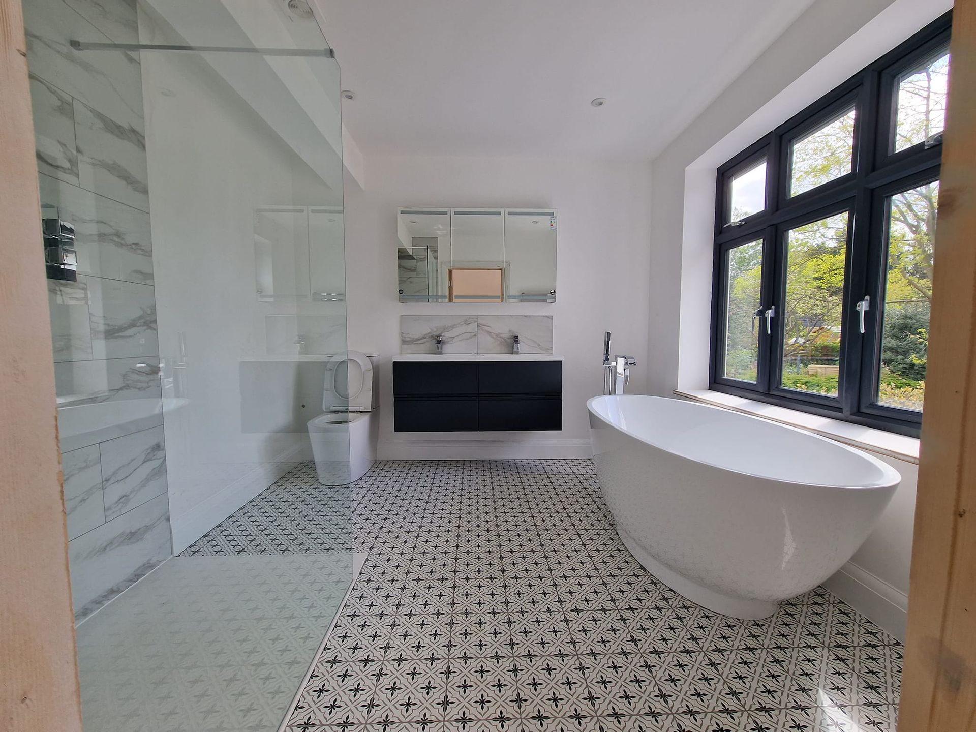 A newly redesigned bathroom with a bathtub , sink , shower and window in Suffolk. Built by Pro Build East Ltd.