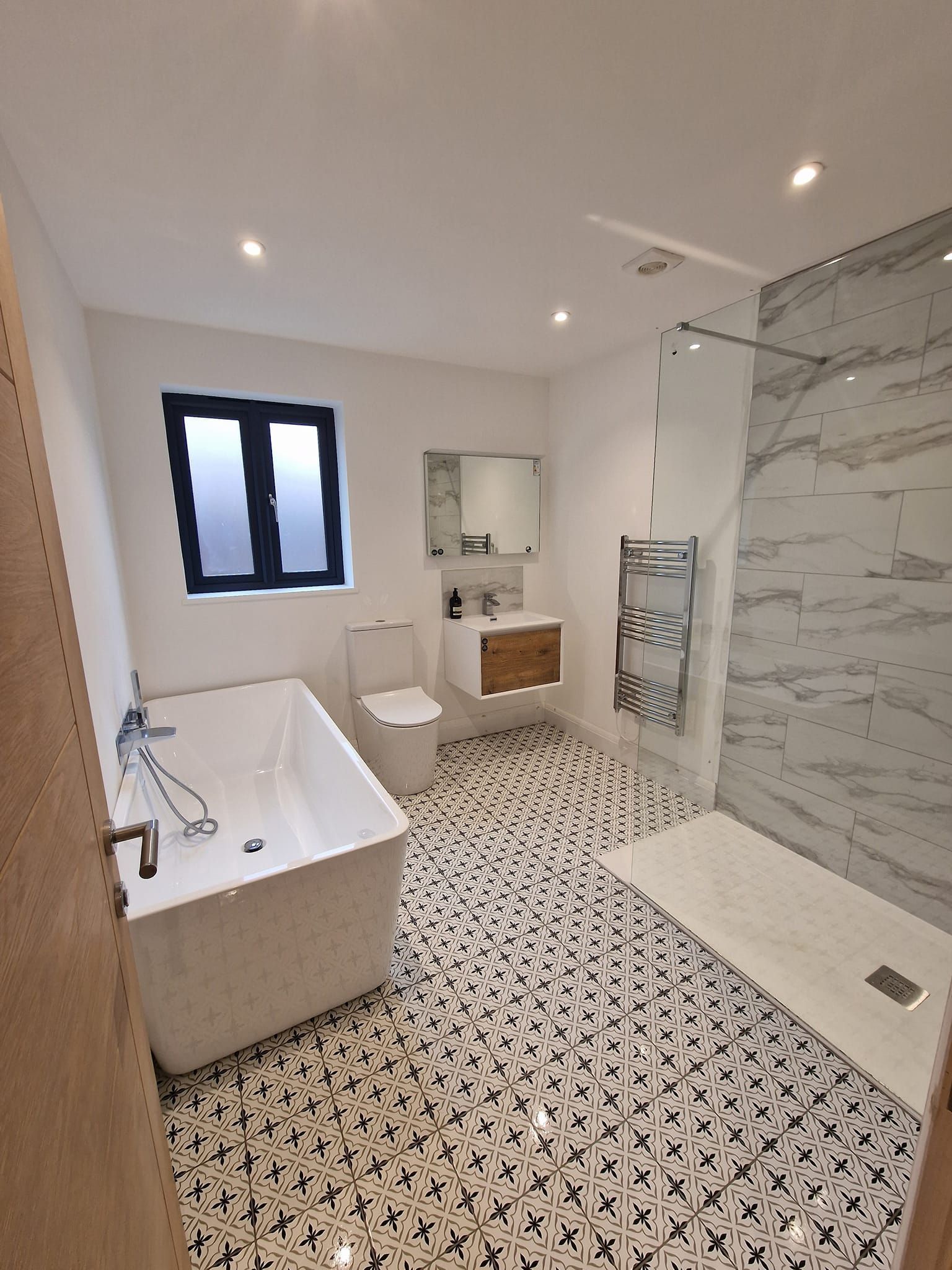 A newly renovated bathroom with a bathtub , sink , shower and window in Suffolk. Built by Pro Build East Ltd.