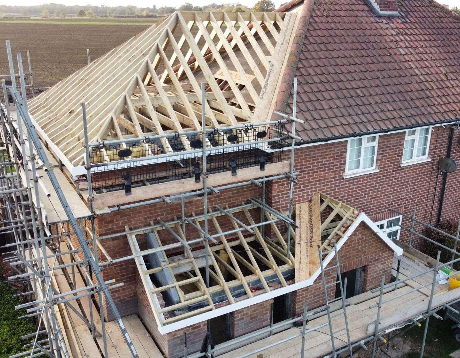 An aerial view of a large two storey side extension under construction in a Suffolk property with scaffolding around it. Built by Pro Build East Ltd.