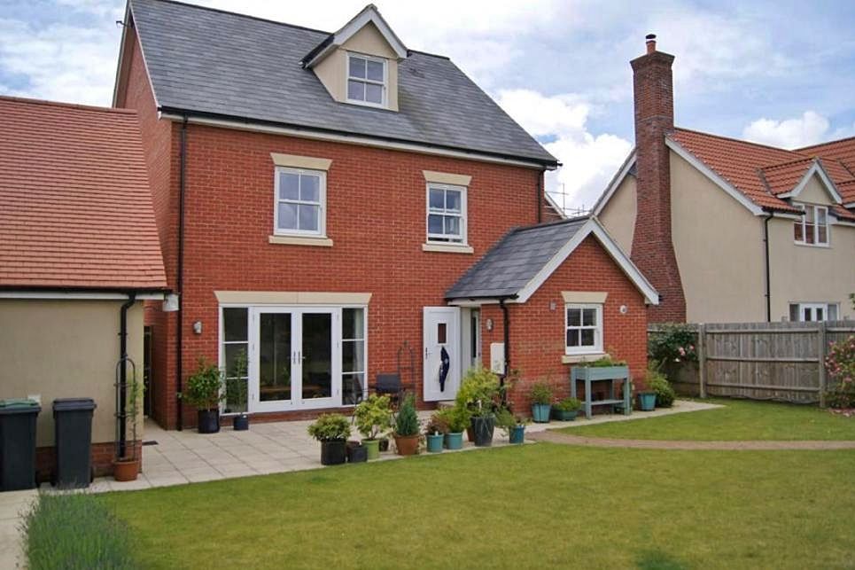 A large brick house with a large lawn in front of it, built by Pro Build East Ltd.