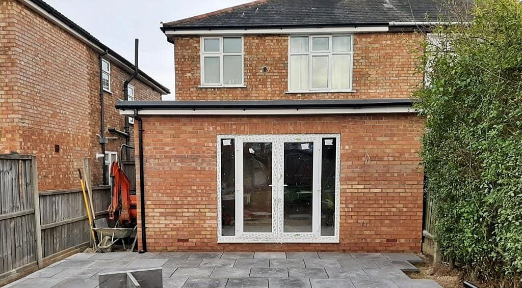 The back of a brick house with a rear extension and patio in front of it, built by Pro Build East Ltd.