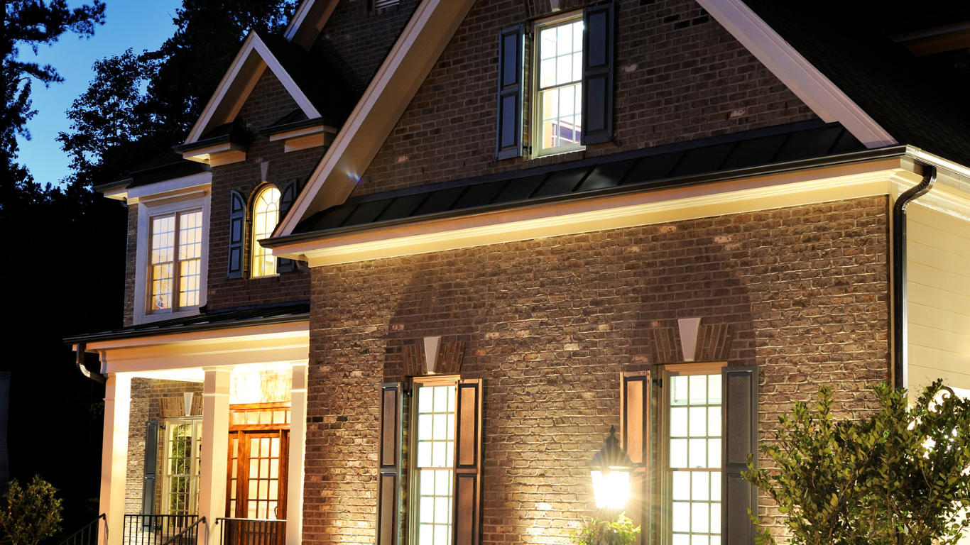 A large brick house with lots of windows is lit up at night.