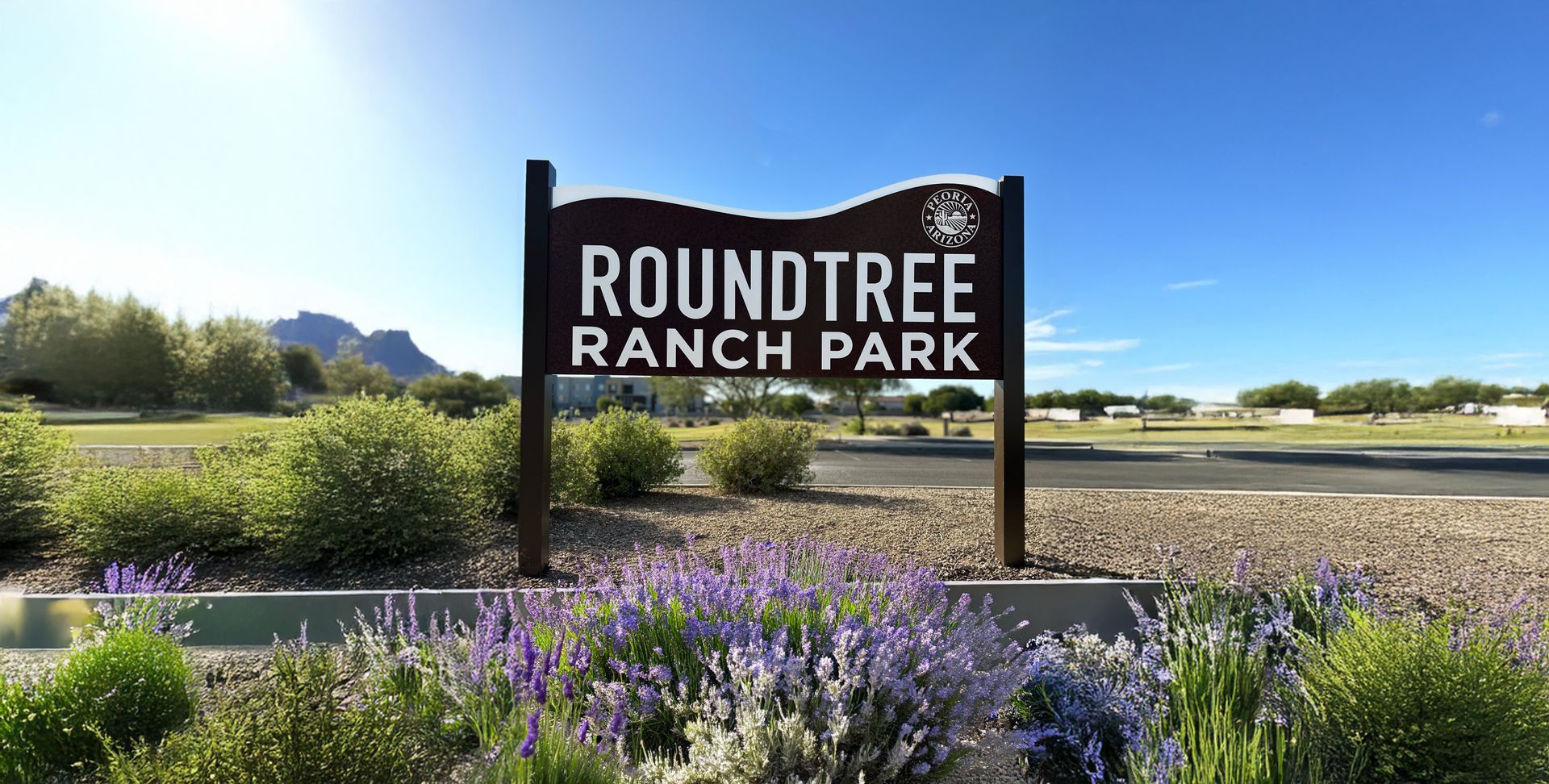 A roundtree ranch park sign is surrounded by purple flowers