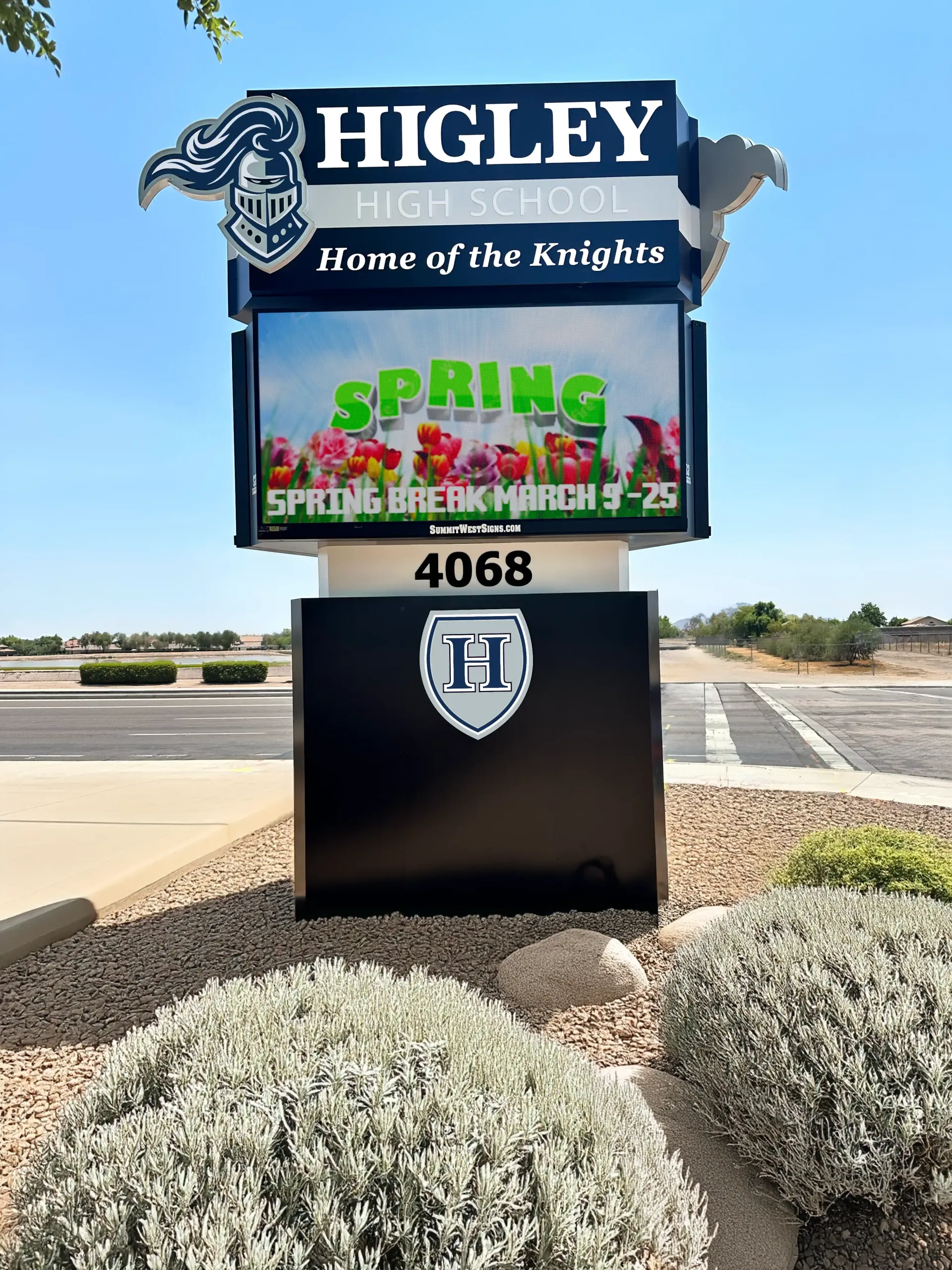 A sign for higley high school is sitting in front of a parking lot.
