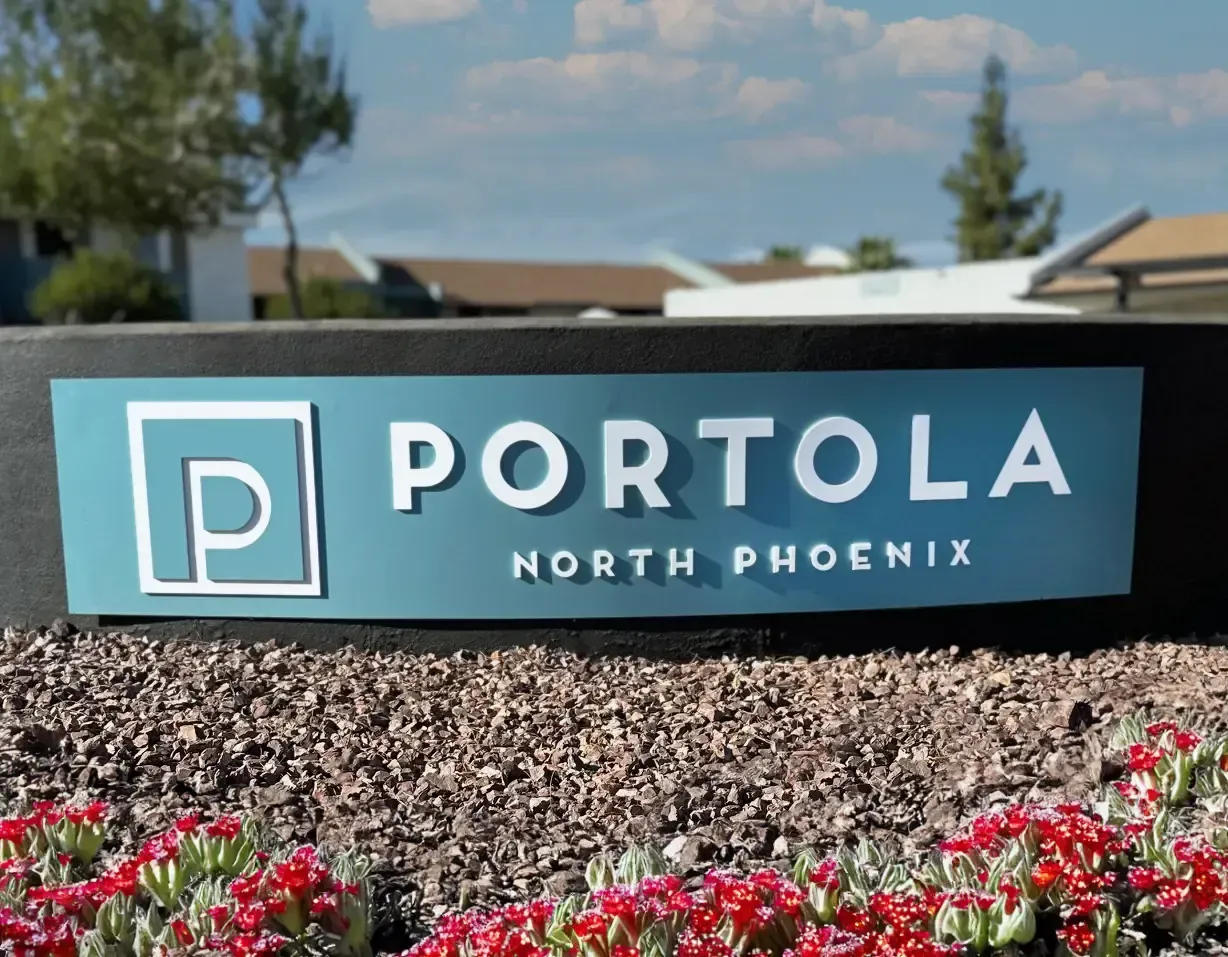 A sign for portola north phoenix is surrounded by flowers