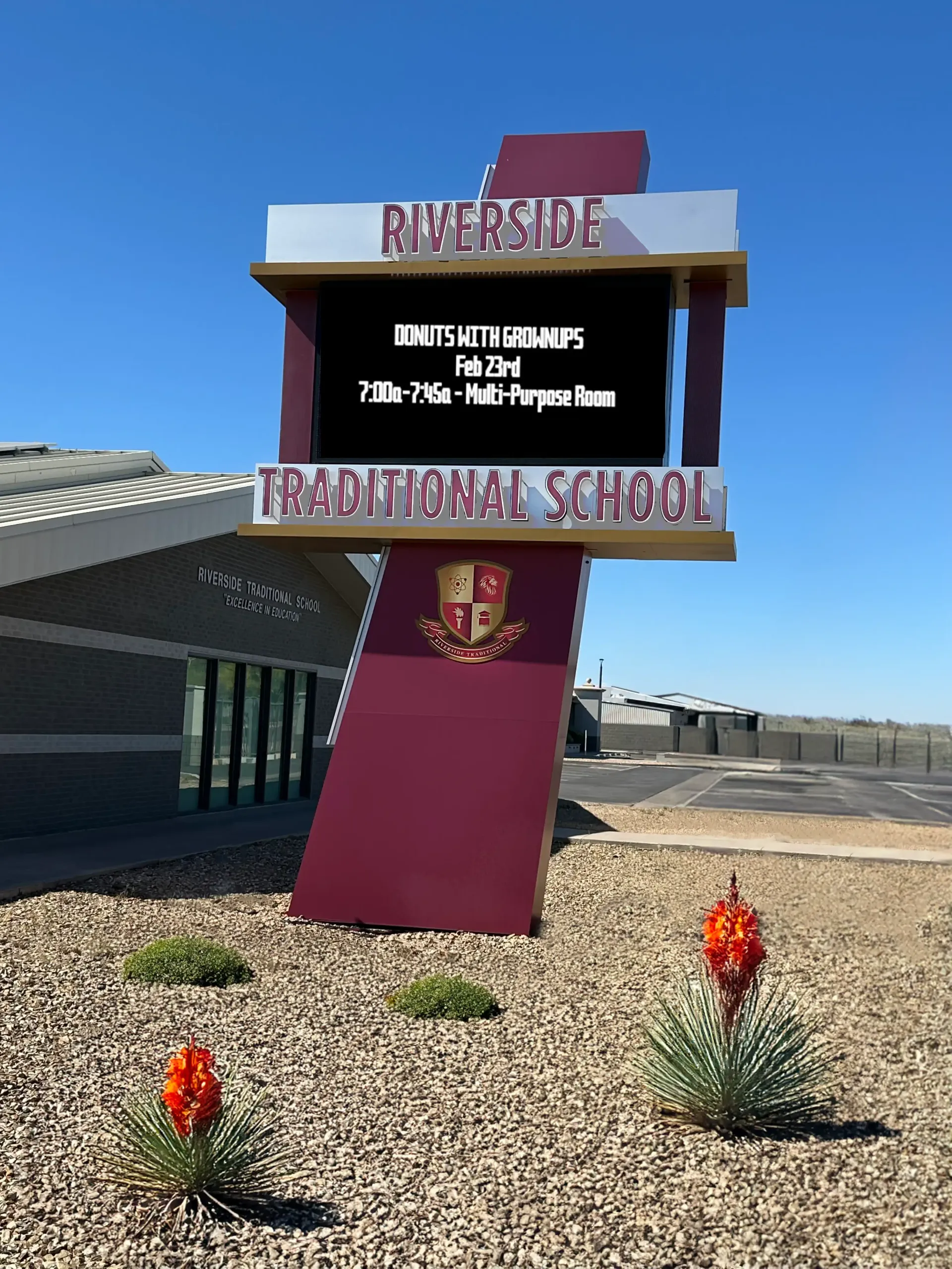 A large sign for riverside educational school is in front of a building.