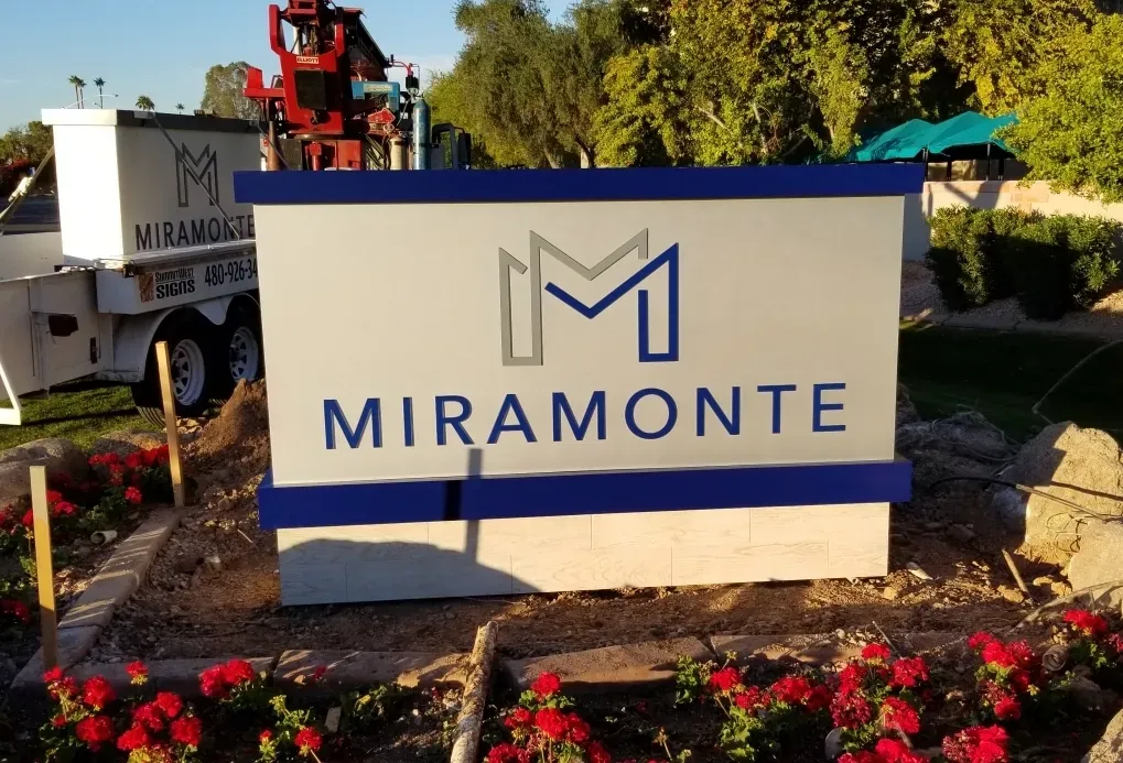 A sign for miramonte is surrounded by red flowers