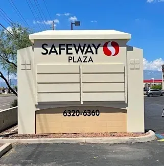 A large white sign for safeway plaza sits in a parking lot